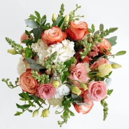 Bouquet of peach and pink roses, lisianthus, and white hydrangea with green snapdragon accents