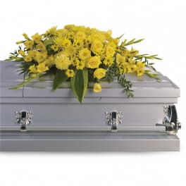 Yellow rose and chrysanthemum casket spray arranged on a closed silver casket