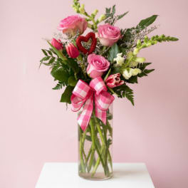 Pink roses and tulips in a glass vase with a checkered bow
