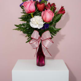 Pink roses and red flowers in a vase with a polka-dot bow