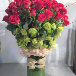 Tall arrangement of red roses and green hydrangeas in a glass vase