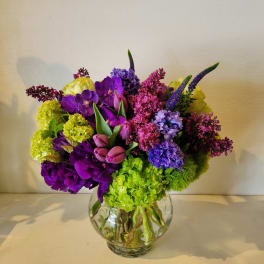 Colorful bouquet in a clear glass vase with purple, pink, yellow, and green blooms