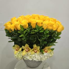 Yellow roses and yellow orchids in a silver vase with white hydrangeas