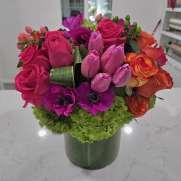 Bright mixed bouquet in a green vase with pink, purple, and orange flowers