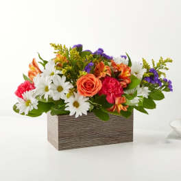 Mixed bouquet in a rectangular wood-look box with daisies, roses, carnations, and purple filler