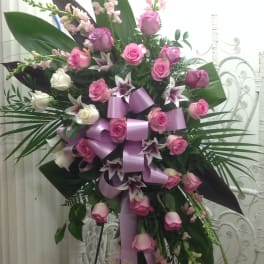 Tall standing floral spray with pink and white roses and lilies, accented by a lavender ribbon