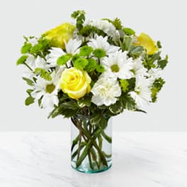 Yellow roses and white daisies in a clear glass vase