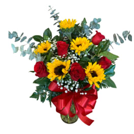Bouquet of red roses and yellow sunflowers in a glass vase with a red ribbon