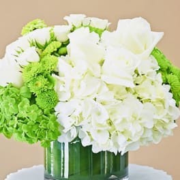 White roses and hydrangeas with bright green blooms in a glass vase