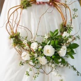 White floral wreath with greenery on a copper wire frame