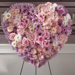 Heart-shaped arrangement of pink and lavender flowers on an easel