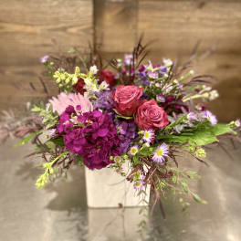 Pink roses and purple flowers arranged in a white box