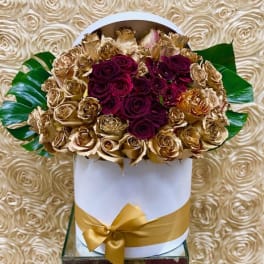 Bouquet of deep red and gold roses in a white hat box with a gold ribbon