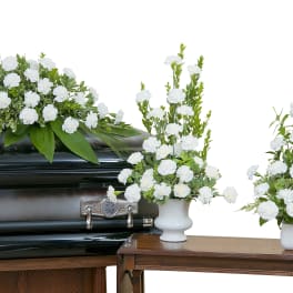 White floral funeral arrangement on a casket with two matching vase arrangements