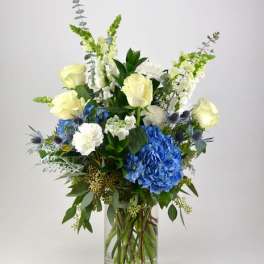 Blue and white floral arrangement in a clear glass vase