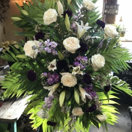 Tall standing floral spray with white roses, lilies, and purple accents