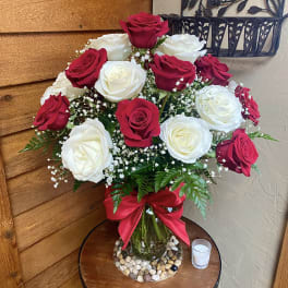 Bouquet of red and white roses in a glass vase with a red ribbon