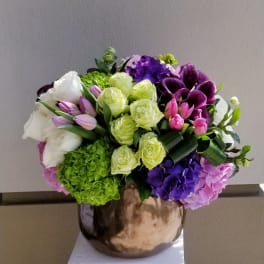 Mixed bouquet of roses, tulips, hydrangeas, and calla lilies in a metallic vase