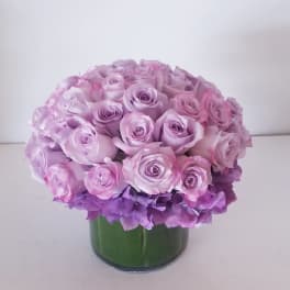 Round bouquet of pink and lavender roses in a green vase