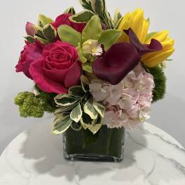 Bright mixed bouquet in a square glass vase