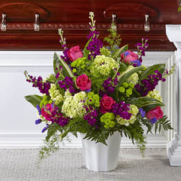 Pink roses and purple flowers arranged in a white vase