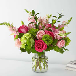 Pink roses and lilies arranged in a clear glass vase
