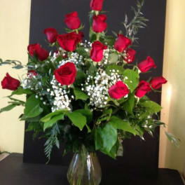 Red roses arranged in a clear glass vase with baby's breath