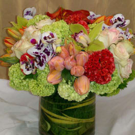 Mixed bouquet in a glass vase with orchids, roses, tulips, and green hydrangeas