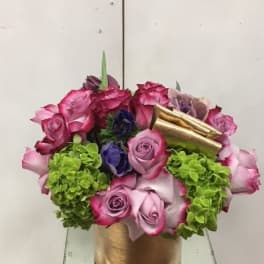 Pink and purple roses with green hydrangeas in a gold container