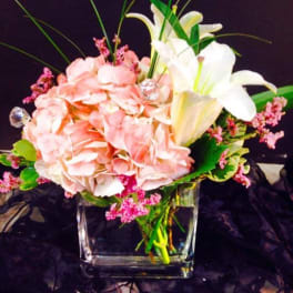Pink hydrangeas and white lilies in a clear glass vase