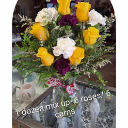 Bouquet of yellow roses and white and purple carnations in a glass vase