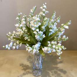 White lily of the valley arrangement in a clear glass vase