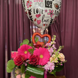 Heart-shaped balloon above a pink flower arrangement in a vase