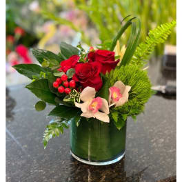 Red roses in a green glass vase with pink orchids