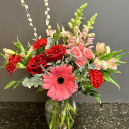 Mixed bouquet with red roses, pink gerbera daisy, and pink lilies in a glass vase