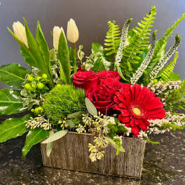 Red roses and a red gerbera daisy in a rectangular vase