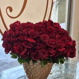 Low arrangement of tightly clustered red roses in a textured metallic vase