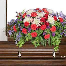 Large floral spray on a wooden casket with red, white, and purple flowers