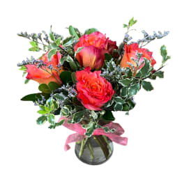 Bouquet of coral roses in a glass vase with a pink ribbon