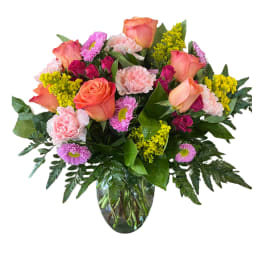 Mixed bouquet of roses, carnations, and daisies in a glass vase