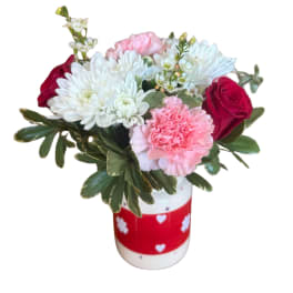 Bouquet of white daisies, pink carnations, and red roses in a decorated vase