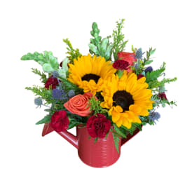 Sunflowers and roses arranged in a red watering can