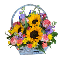 Basket arrangement with sunflowers, carnations, and purple flowers