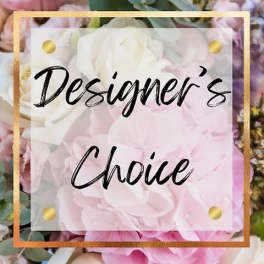 Pastel pink and white flowers with a transparent square sign reading 'Designer’s Choice' in black script