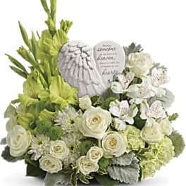 White and green floral arrangement with angel wings and a memorial stone