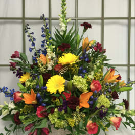 Large mixed flower arrangement in a basket with lilies, gerberas, and delphinium