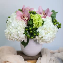 Pink orchids and white hydrangeas arranged in a pale vase