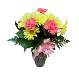 Pink carnations and yellow daisies in a glass vase with a pink ribbon