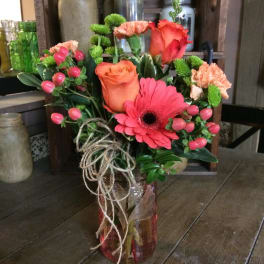 Bouquet of pink and orange flowers in a glass jar vase