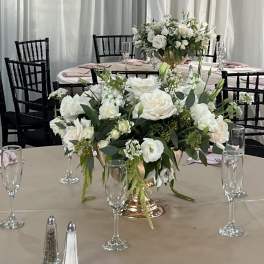 White floral centerpieces on round banquet tables with pink napkins